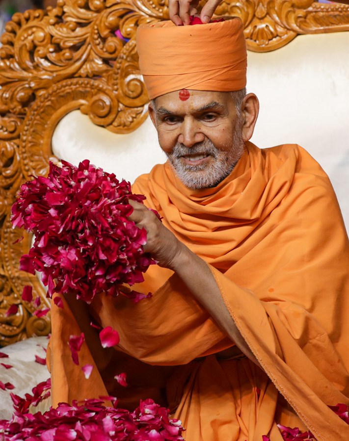 Swamishri showers flower petals on sadhus