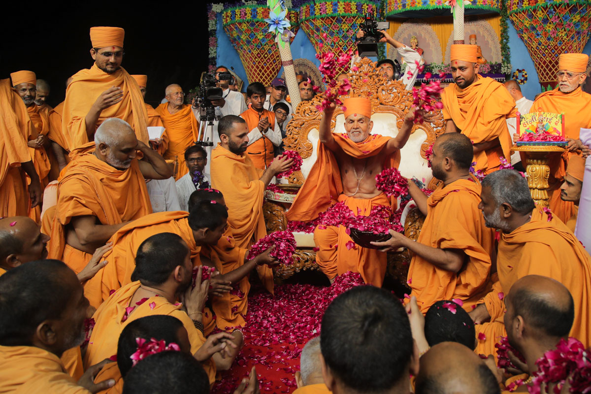 Swamishri showers flower petals on sadhus