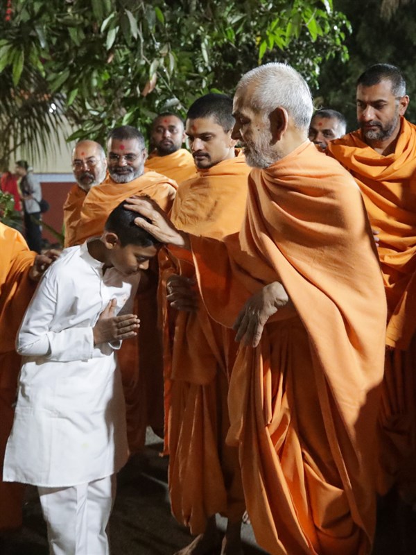 Swamishri blesses a child in the mandir grounds