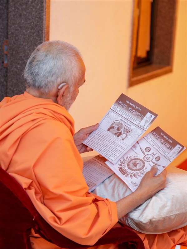 Swamishri reads the monthly magazine for bal karyakars, 'Bal Ghanshyam'