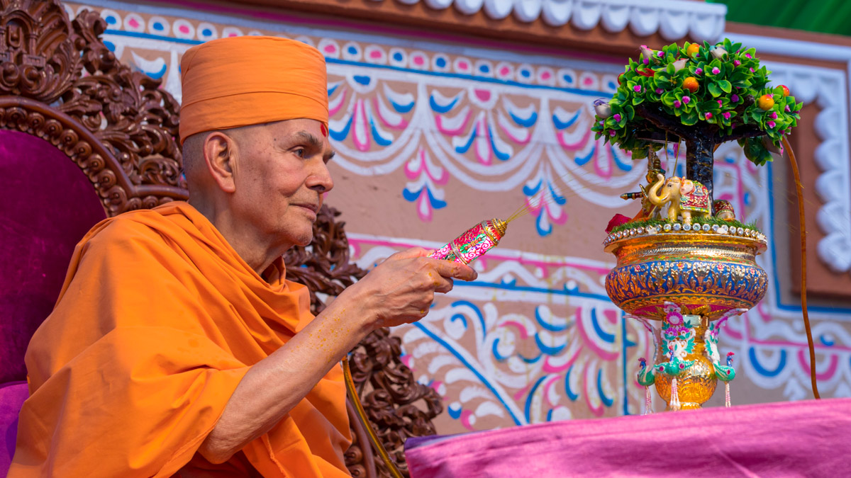 Swamishri sprays saffron-scented water on Shri Harikrishna Maharaj