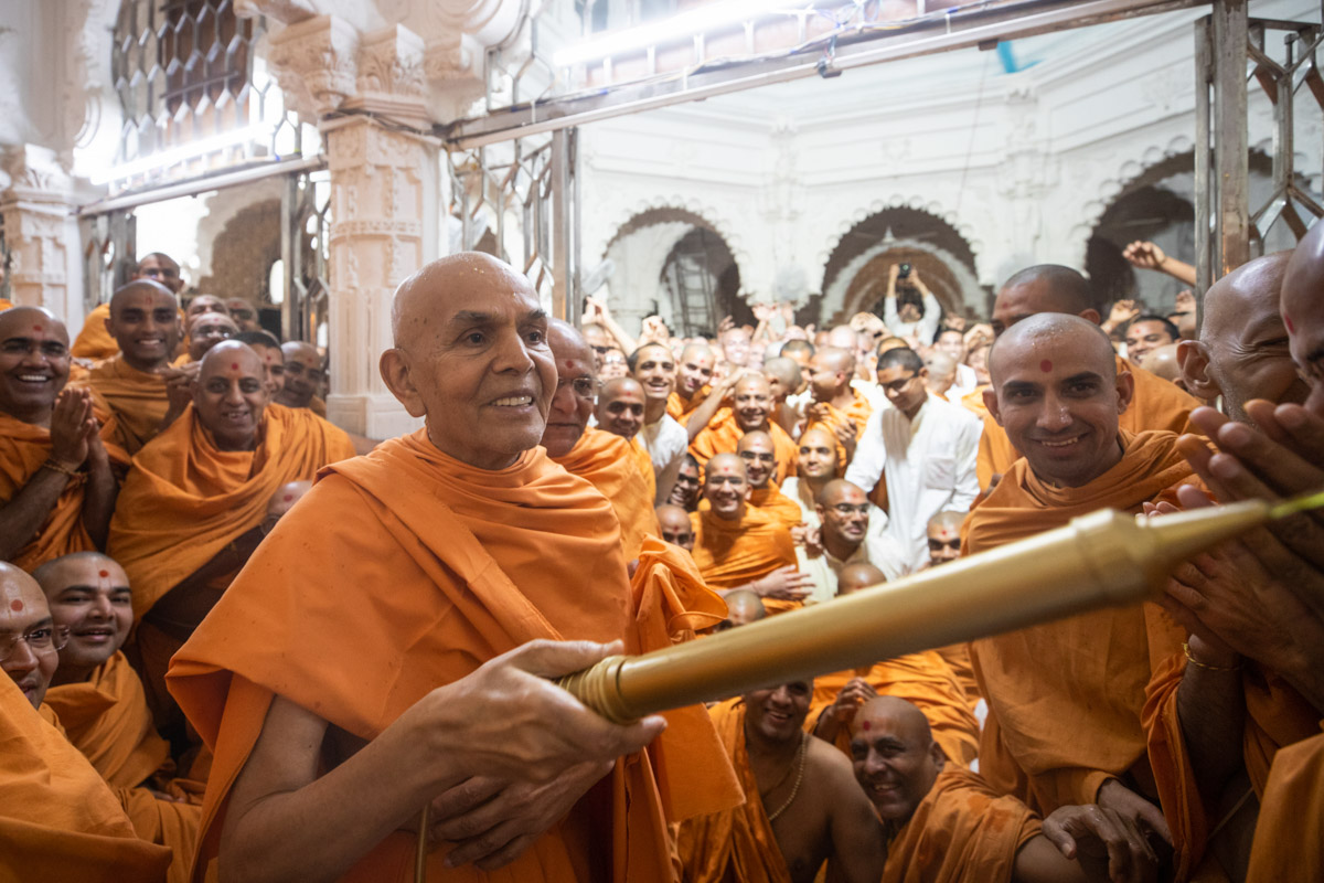 Swamishri sprays saffron-scented water on sadhus
