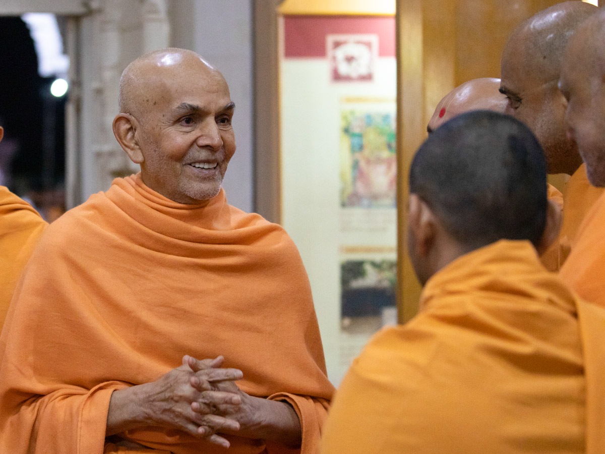 Swamishri converses with sadhus in the Rang Mandap