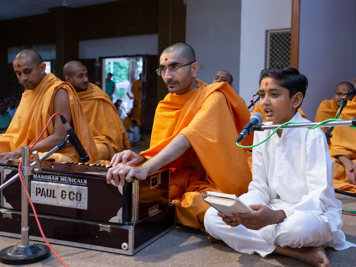 A child sings kirtans in Swamishri's morning puja