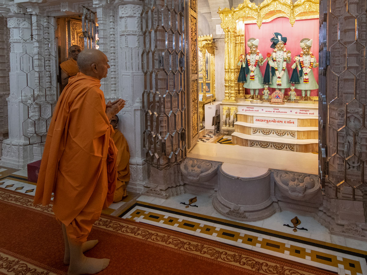 Swamishri engrossed in the darshan of Bhagwan Swaminarayan, Aksharbrahman Gunatitanand Swami and Shri Gopalanand Swami