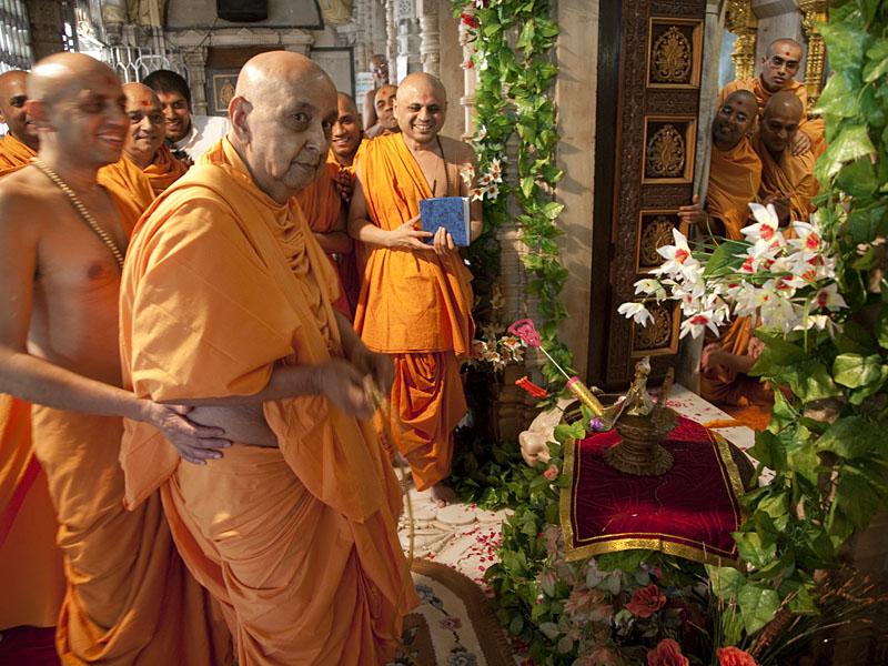 Swamishri sprays color on Thakorji on symbolic celebration of Pushpadolotsav