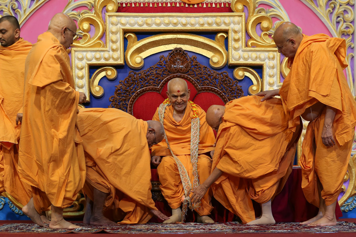 Senior sadhus honor Swamishri with a garland