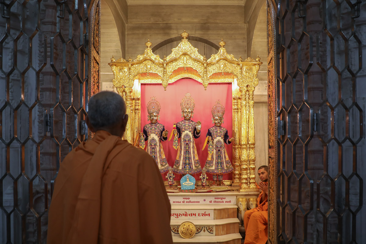 Swamishri engrossed in darshan of Shri Bhagwan Swaminarayan, Aksharbrahman Gunatitanand Swami and Shri Gopalanand Swami