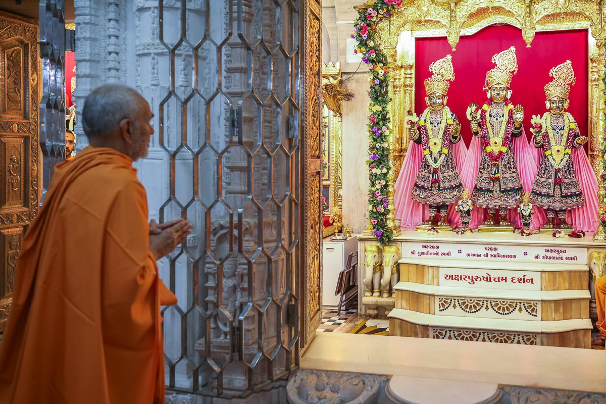 Swamishri engrossed in the darshan of Bhagwan Swaminarayan, Aksharbrahman Gunatitanand Swami and Shri Gopalanand Swami