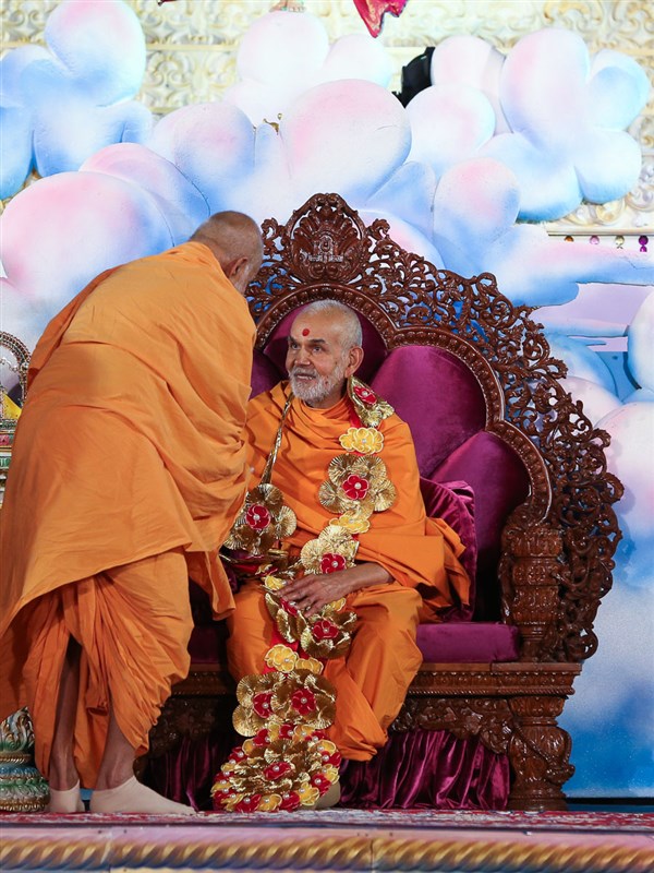 Bhagwatpriya Swami honors Swamishri with a garland