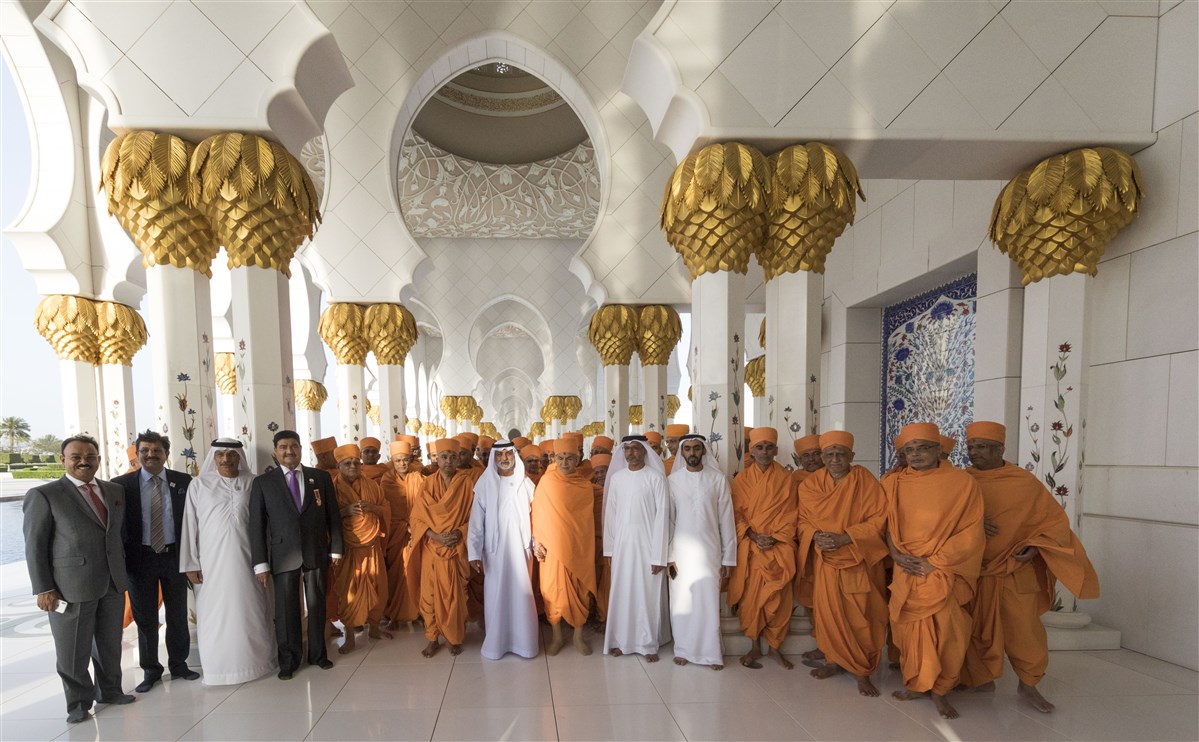 HH Mahant Swami Maharaj, HE Sheikh Nahyan bin Mubarak Al Nahyan, BAPS sadhus and others stand in the corridor of 1,096 pillars