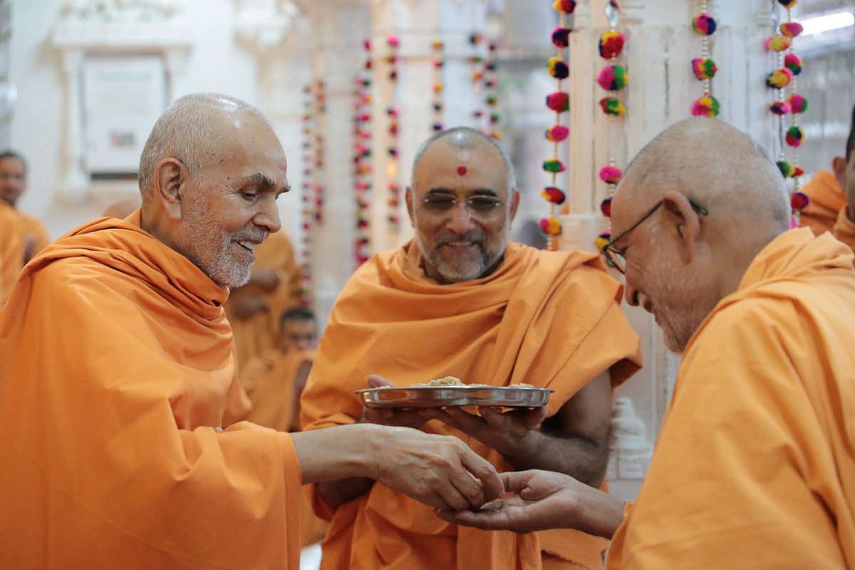 Swamishri gives prasad to Pujya Bhaktipriya Swami (Kothari Swami)