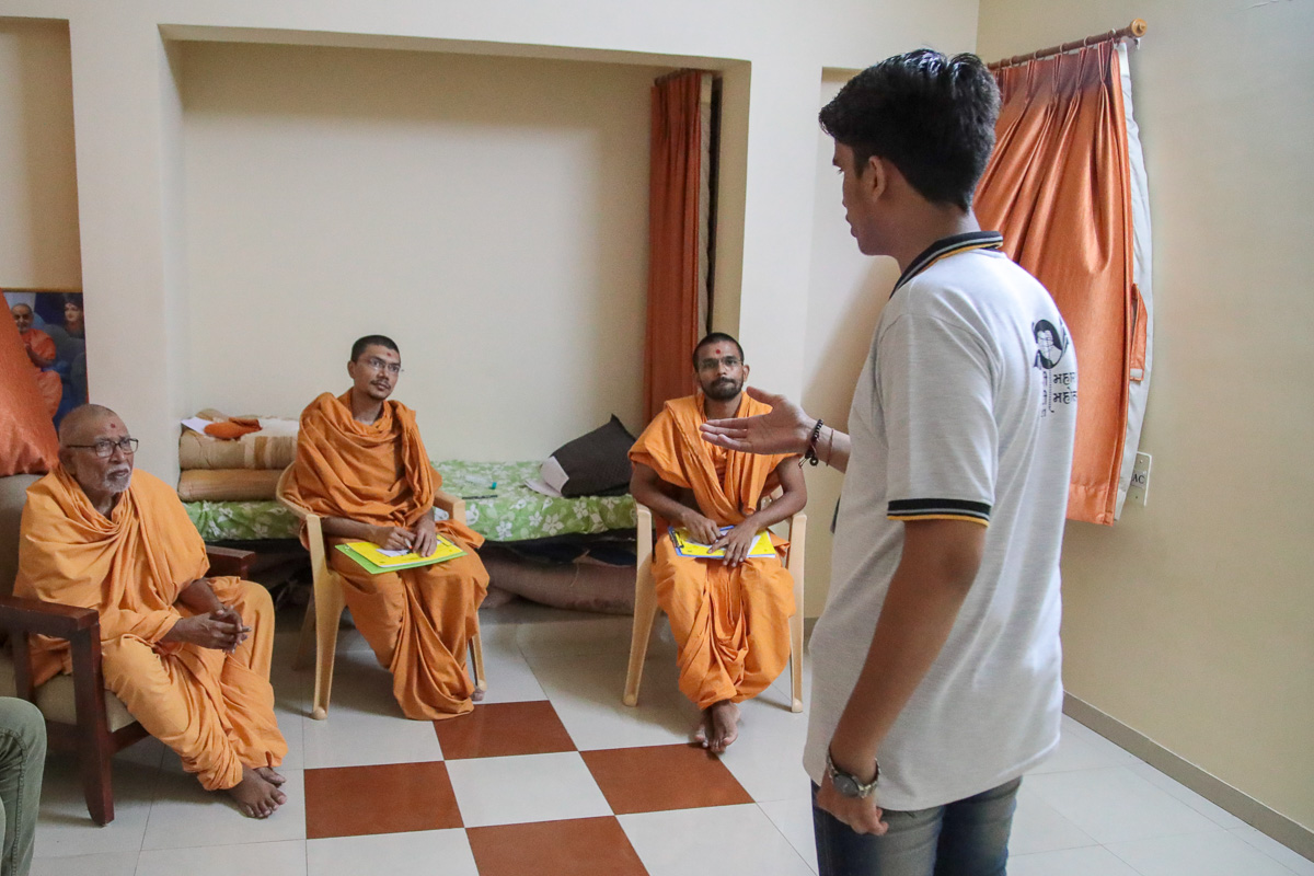 Pujya Kothari Swami observes a youth participating in the Speech competition