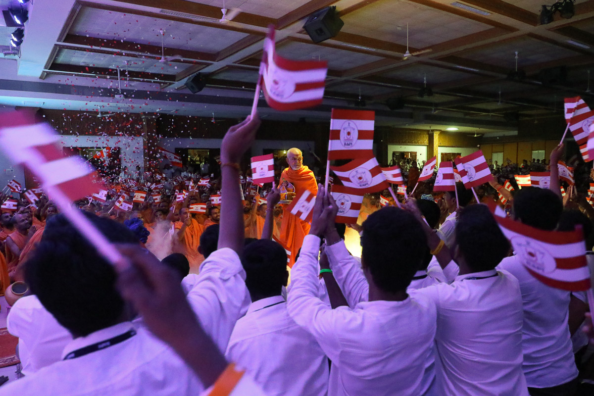 Youths welcome Swamishri by waving BAPS flags