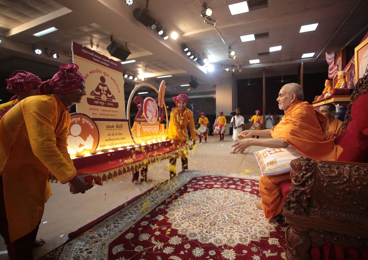 Swamishri showers flower petals on a large replica of the adhiveshan prizes