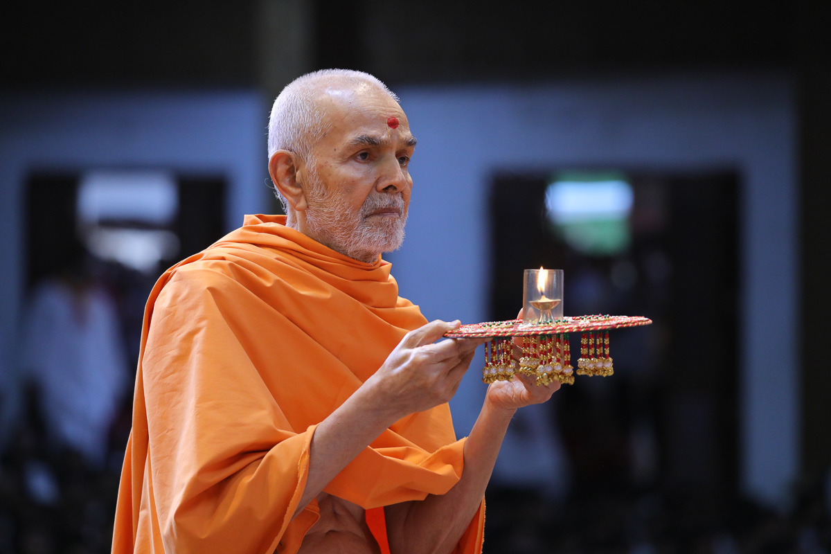 Swamishri performs the evening arti in the evening assembly