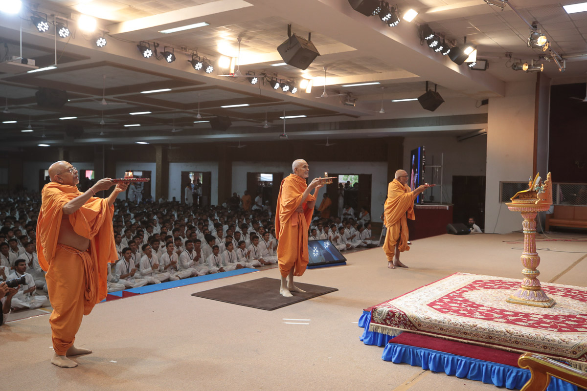 Swamishri and senior sadhus perform the evening arti