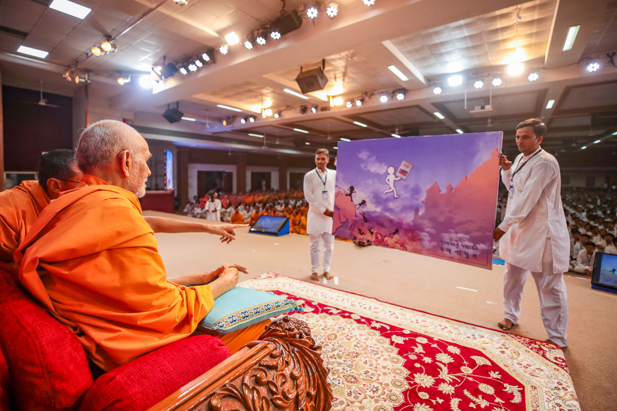 Swamishri observes a poster prepared for the competition