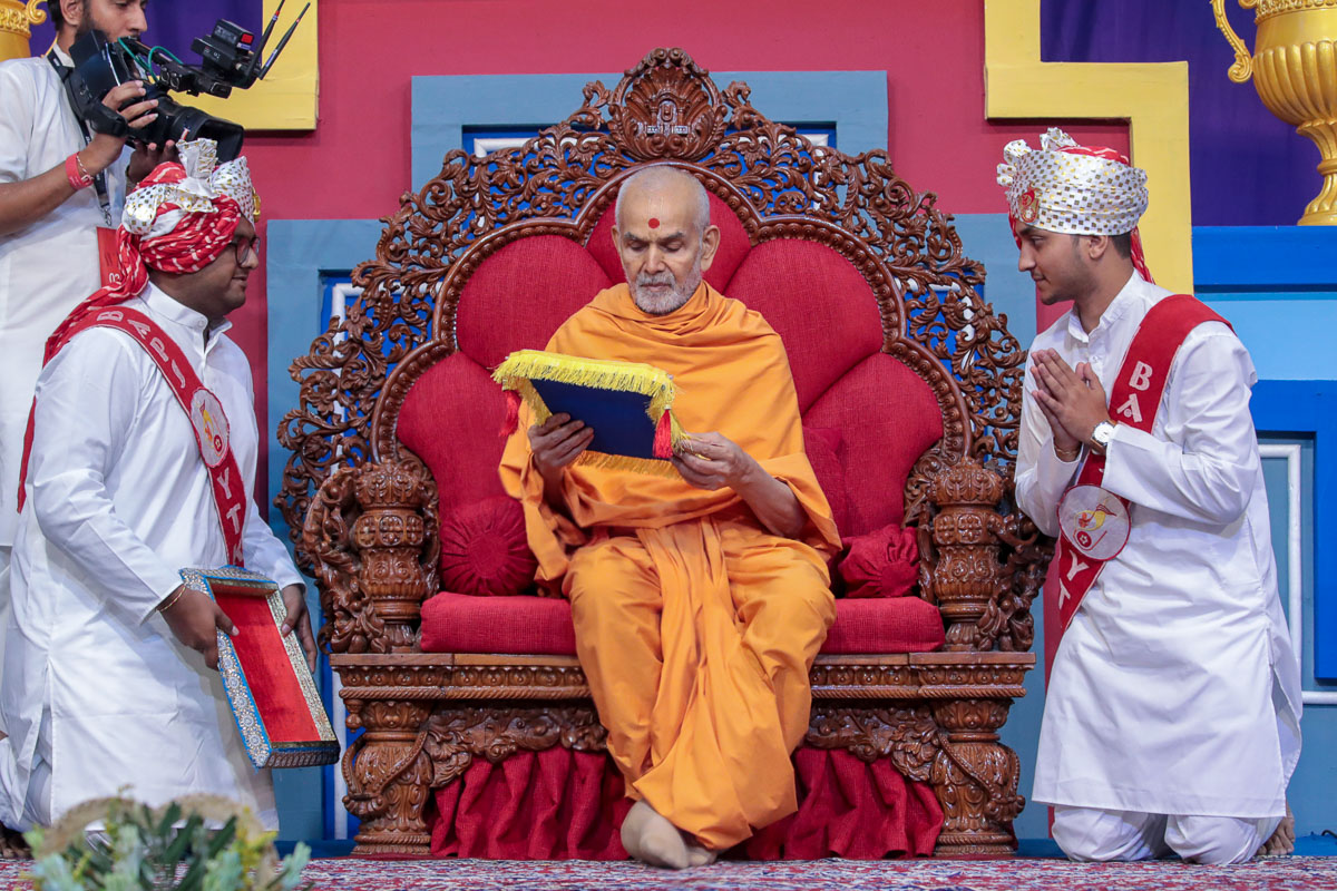 Swamishri accepts an invitation card from the 20th batch of the Yuva Talim Kendra (YTK)