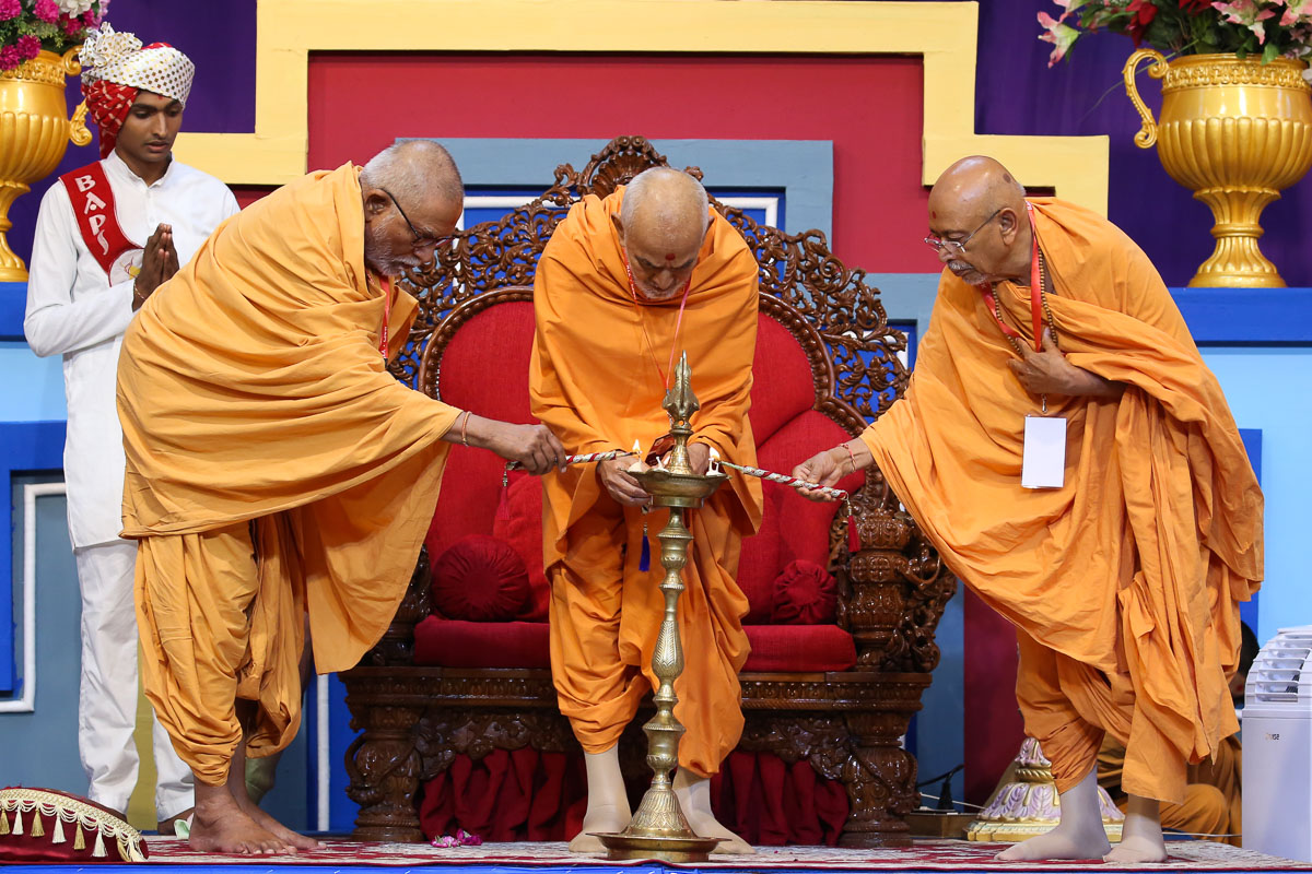 Swamishri, Pujya Kothari Swami and Pujya Tyagvallabh Swami light the inaugural lamp for 20th batch of the Yuva Talim Kendra (YTK)