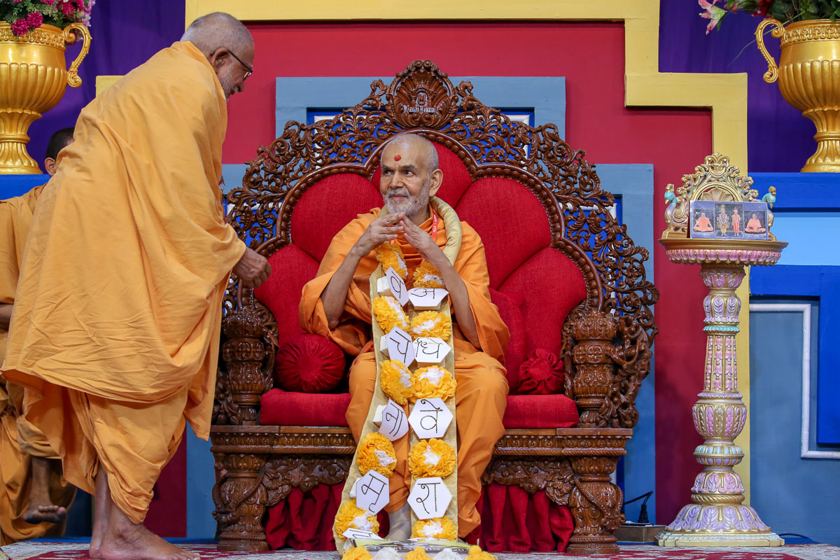 Pujya Kothari Swami honors Swamishri with a garland