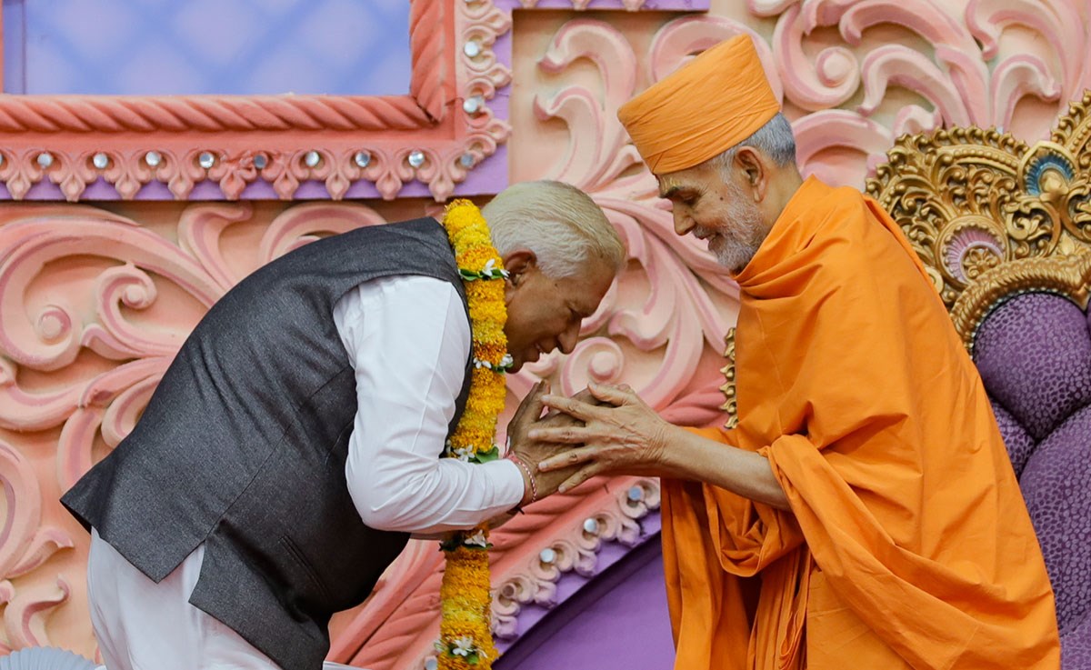 Swamishri honors Shri Vajubhai Vala with a garland