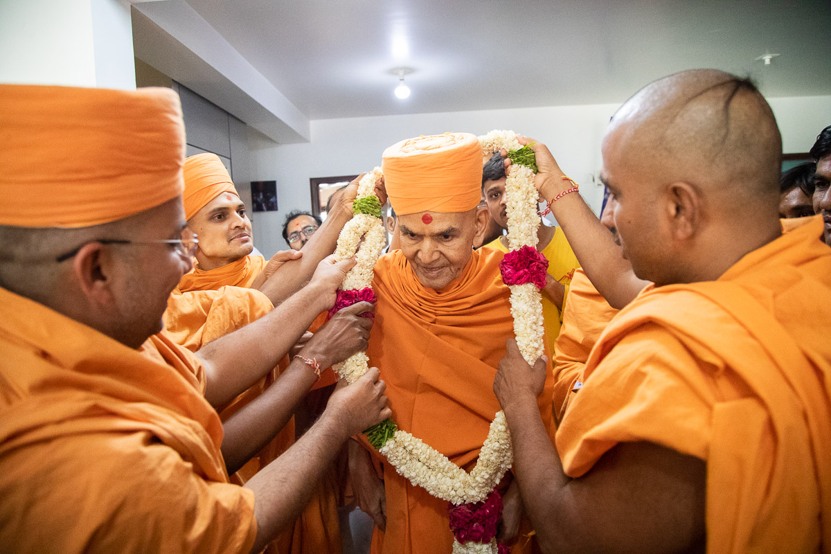 Sadhus honor Swamishri with a garland as he departs from Morbi