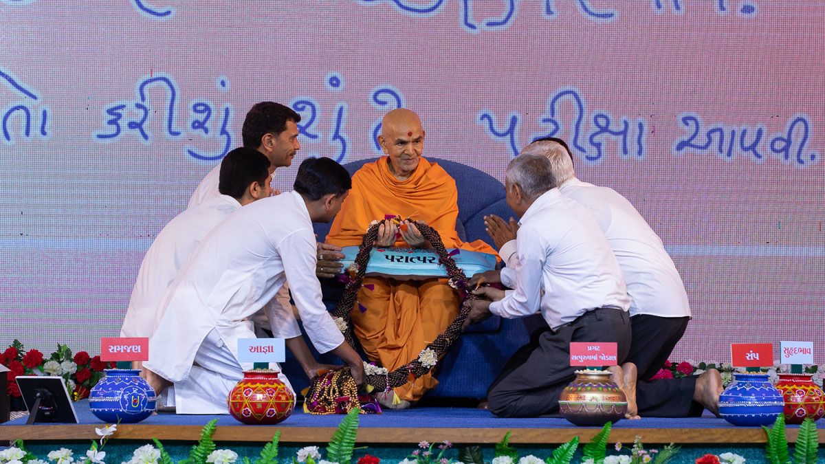 Satsang Exam karyakars honor Swamishri with a garland