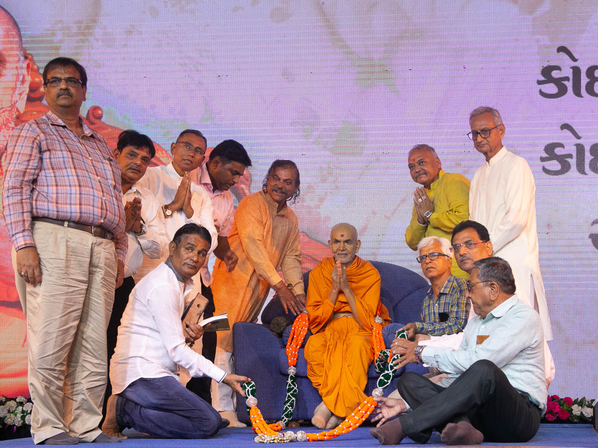 Leading members of Ahmedabad Vepari Mahajan honor Swamishri with a garland