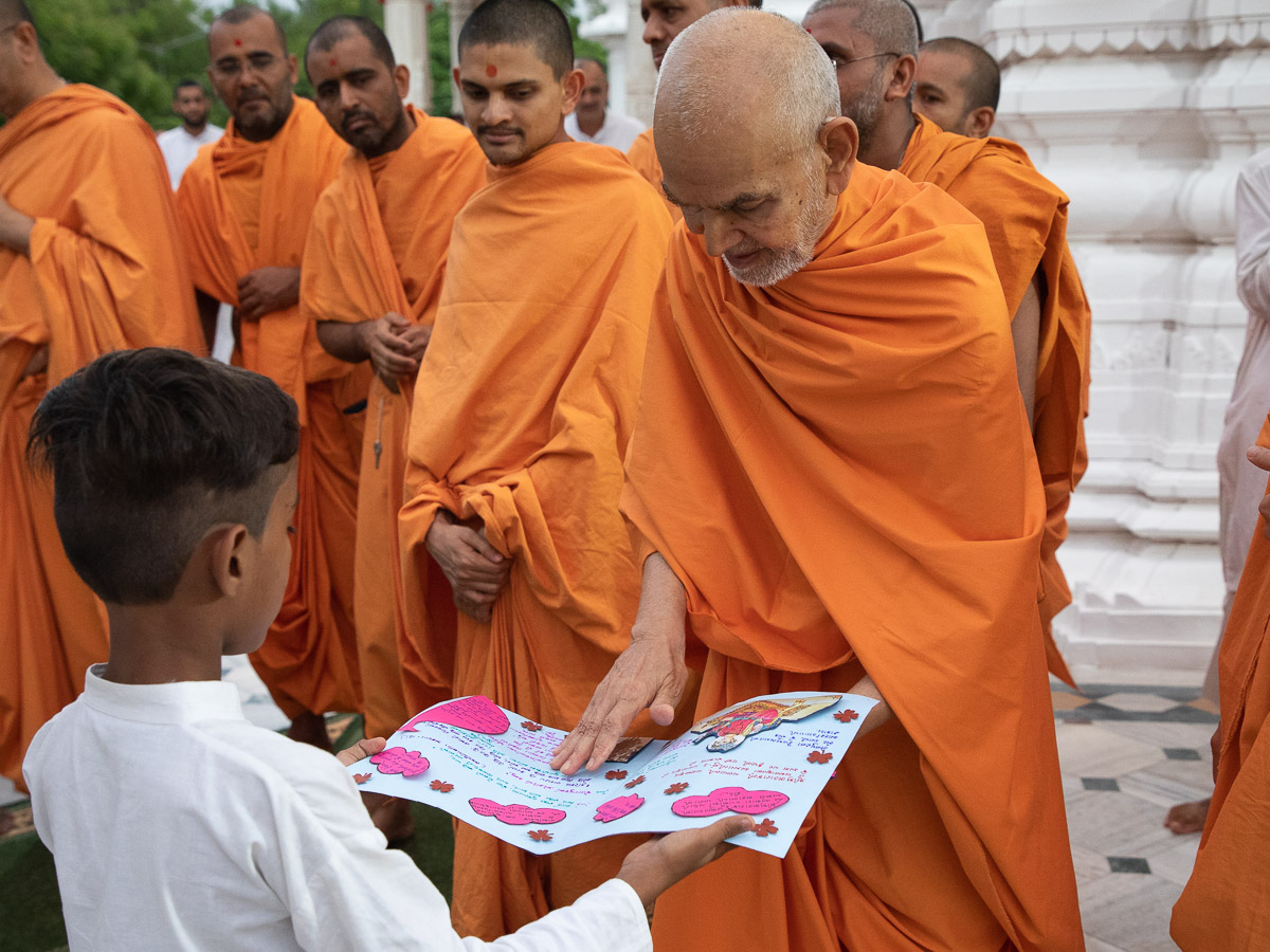 Swamishri sanctifies a card made by a child