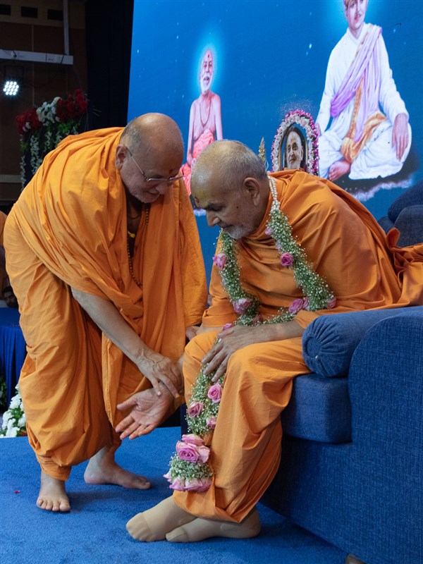 Pujya Ishwarcharan Swami honors Swamishri with a garland