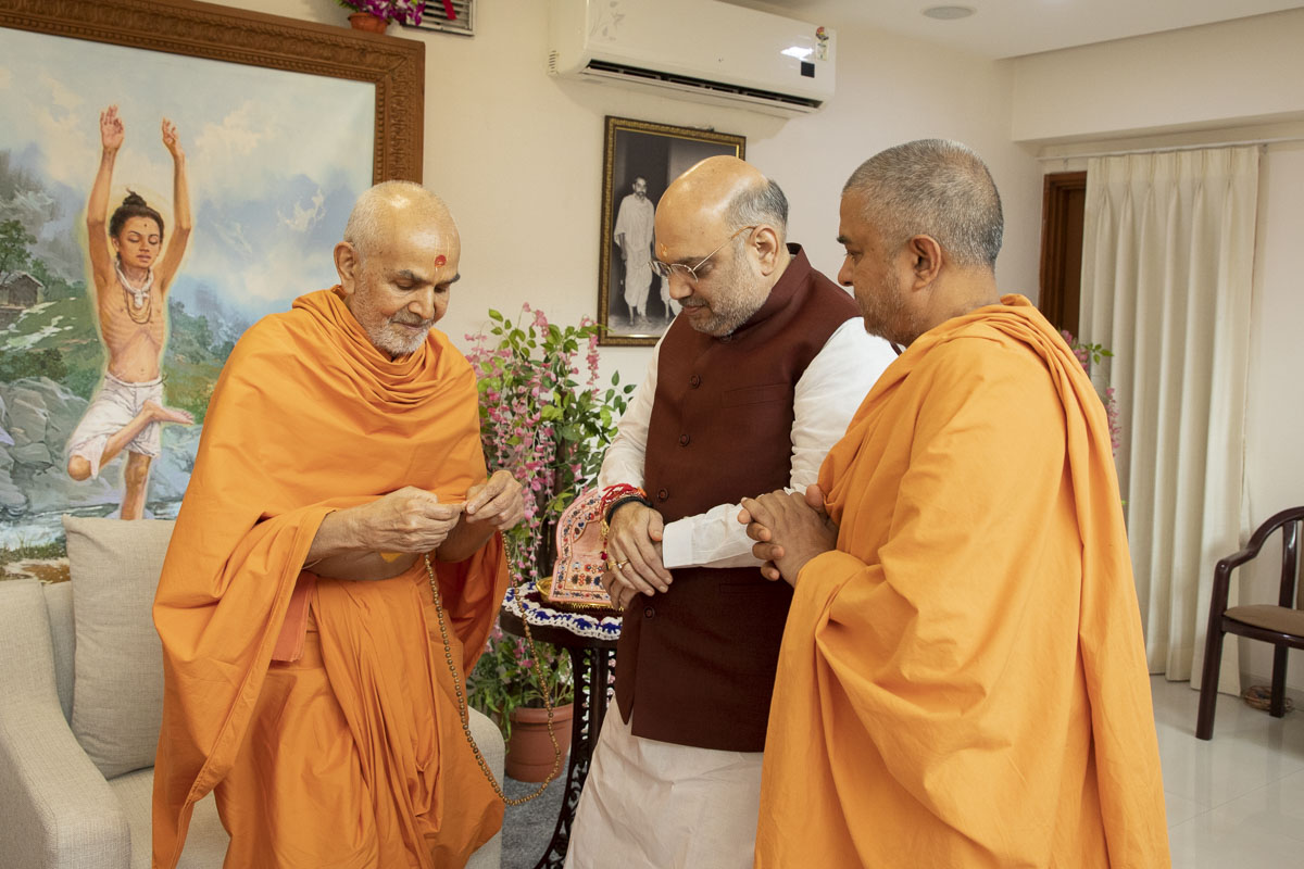 Swamishri sanctifies a mala before presenting it to Shri Amit Shah