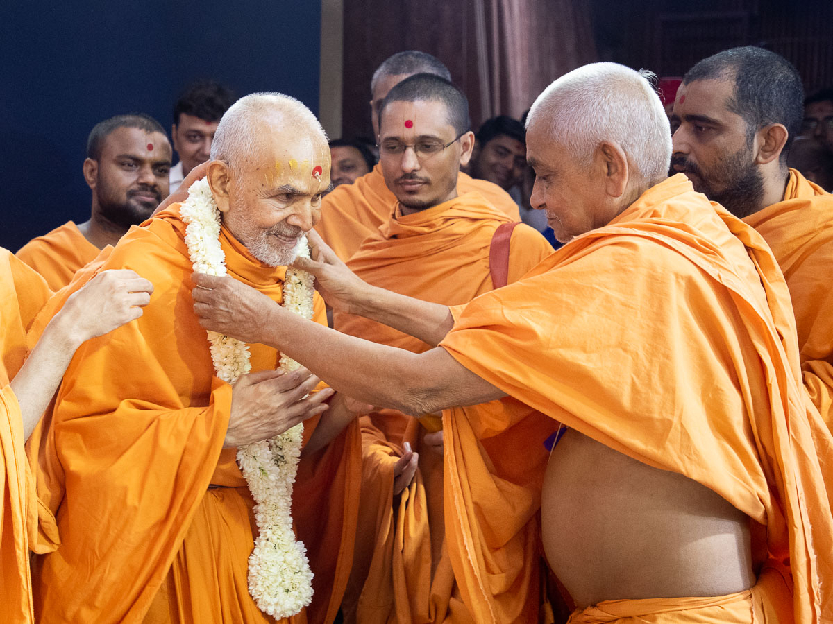 Satsangijivan Swami honors Swamishri with a garland