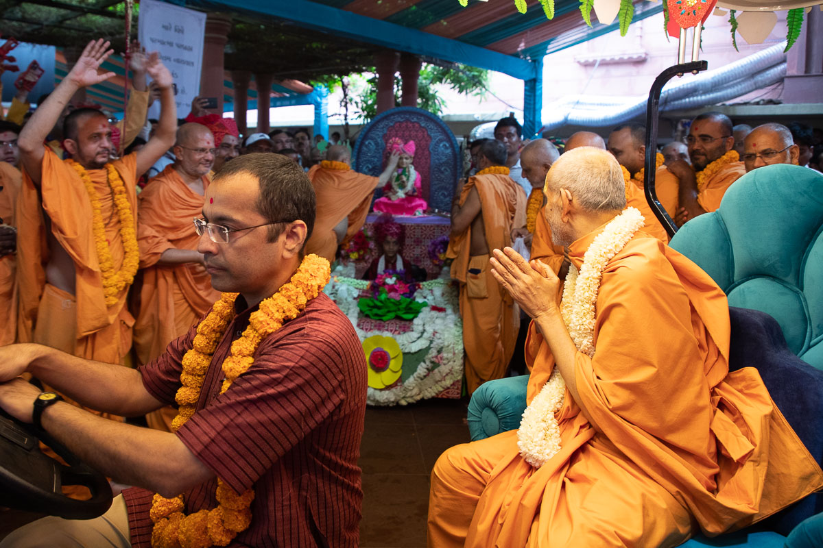 Swamishri engrossed in darshan while Pujya Ishwarcharan Swami performs pujan of Bhagwan Swaminarayan