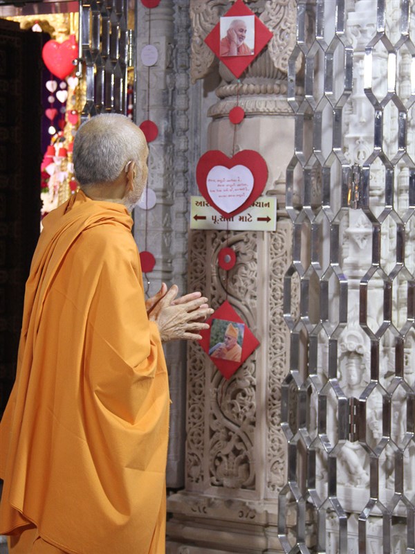 Swamishri observes a photo of Brahmaswarup Pramukh Swami Maharaj