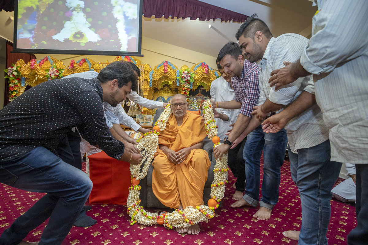 Devotees honor Pujya Bhaktipriya Swami (Pujya Kothari Swami) with a garland