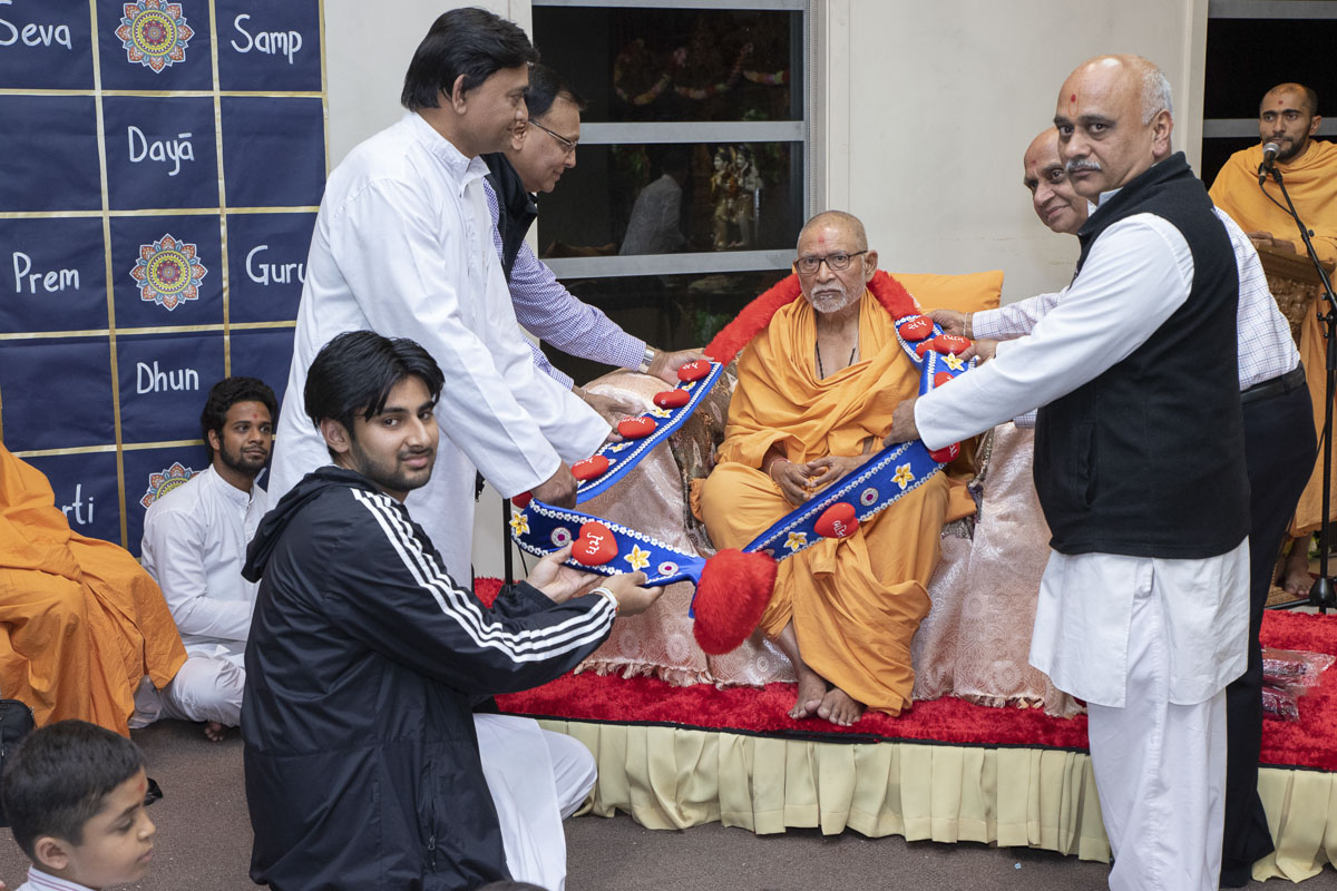 Devotees honor Pujya Kothari Swami with a garland