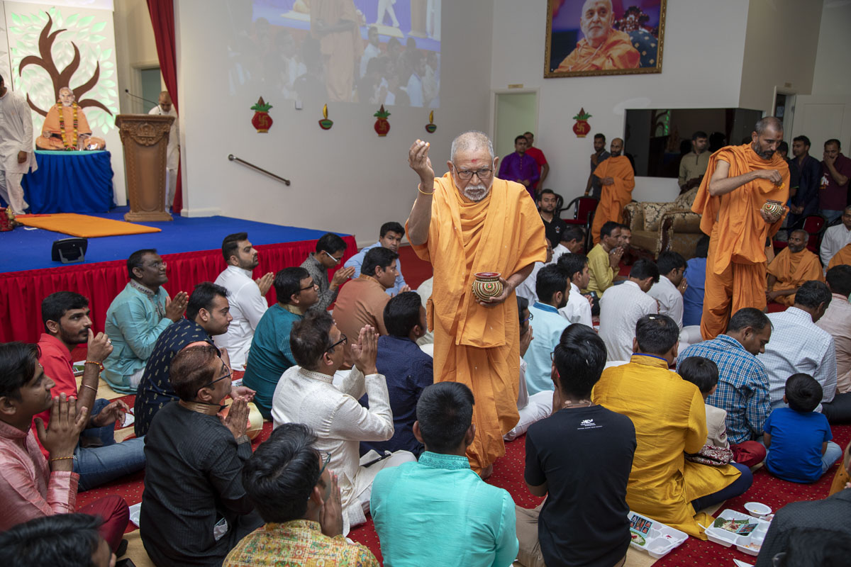 Pujya Kothari Swami showers akshat (rice grains) on devotees