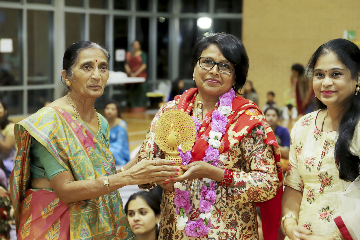 A devotee presents a memento to an invited guest