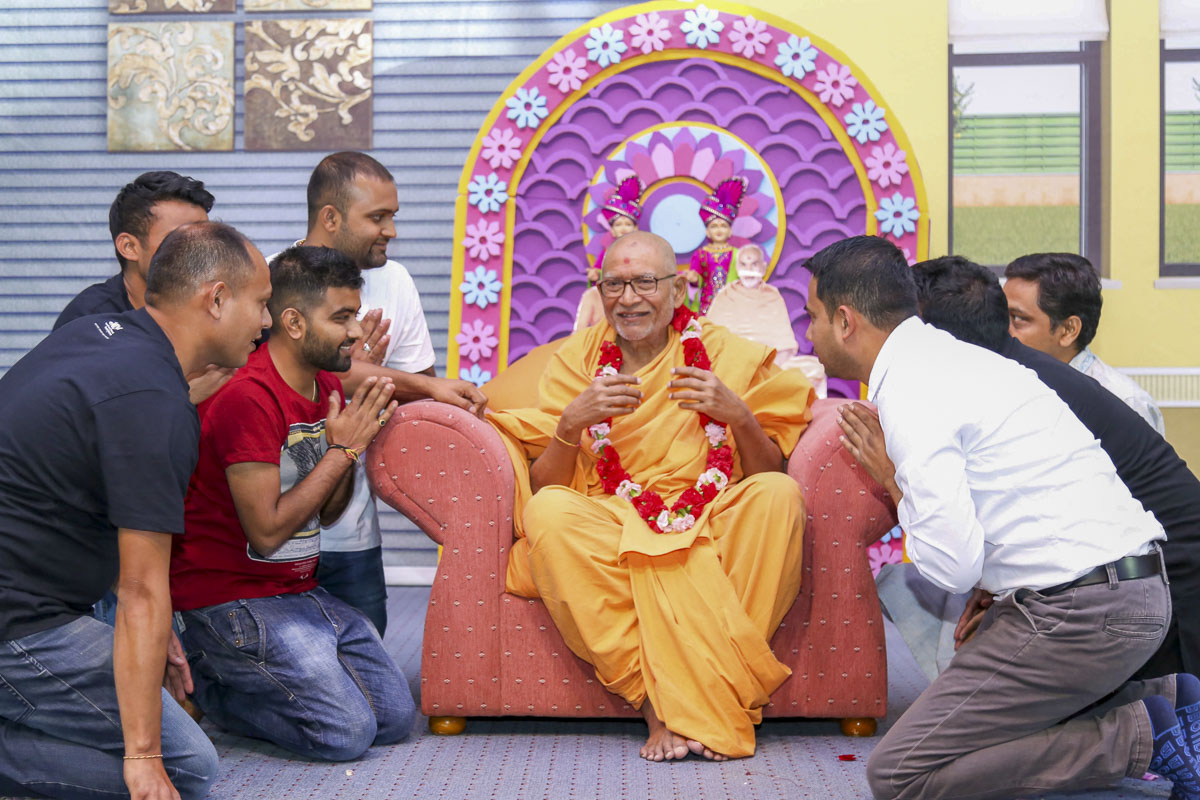 Devotees honor Pujya Kothari Swami with a garland