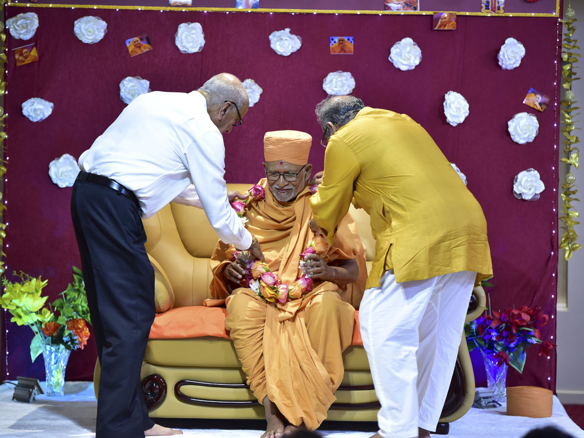 Devotees welcome Pujya Kothari Swami with a garland