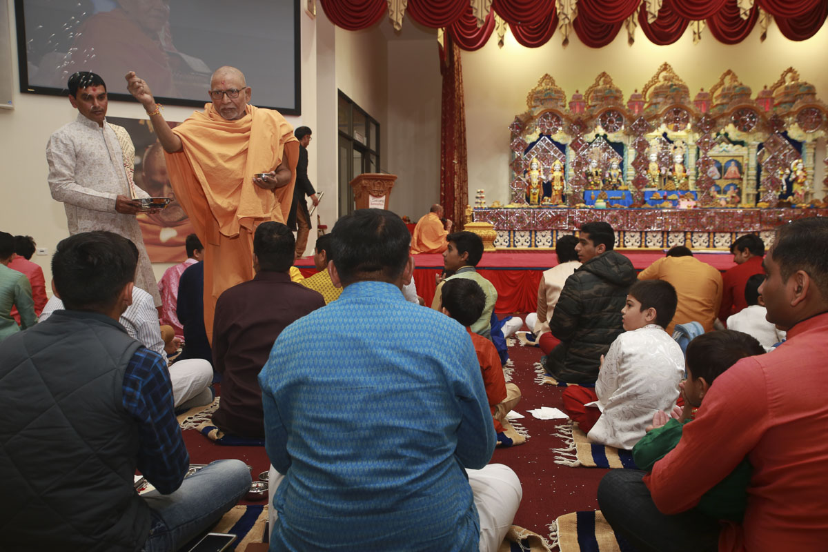 Pujya Kothari Swami showers akshat (rice grains) on devotees