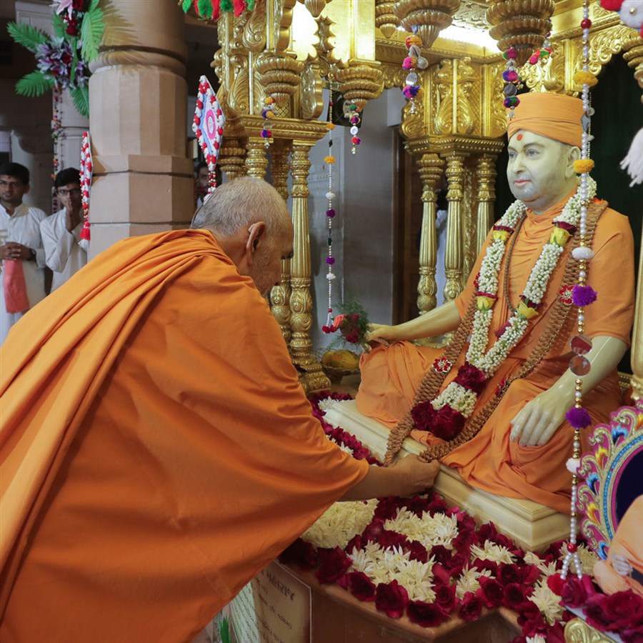 Swamishri observes a garland offered to Brahmaswarup Pramukh Swami Maharaj