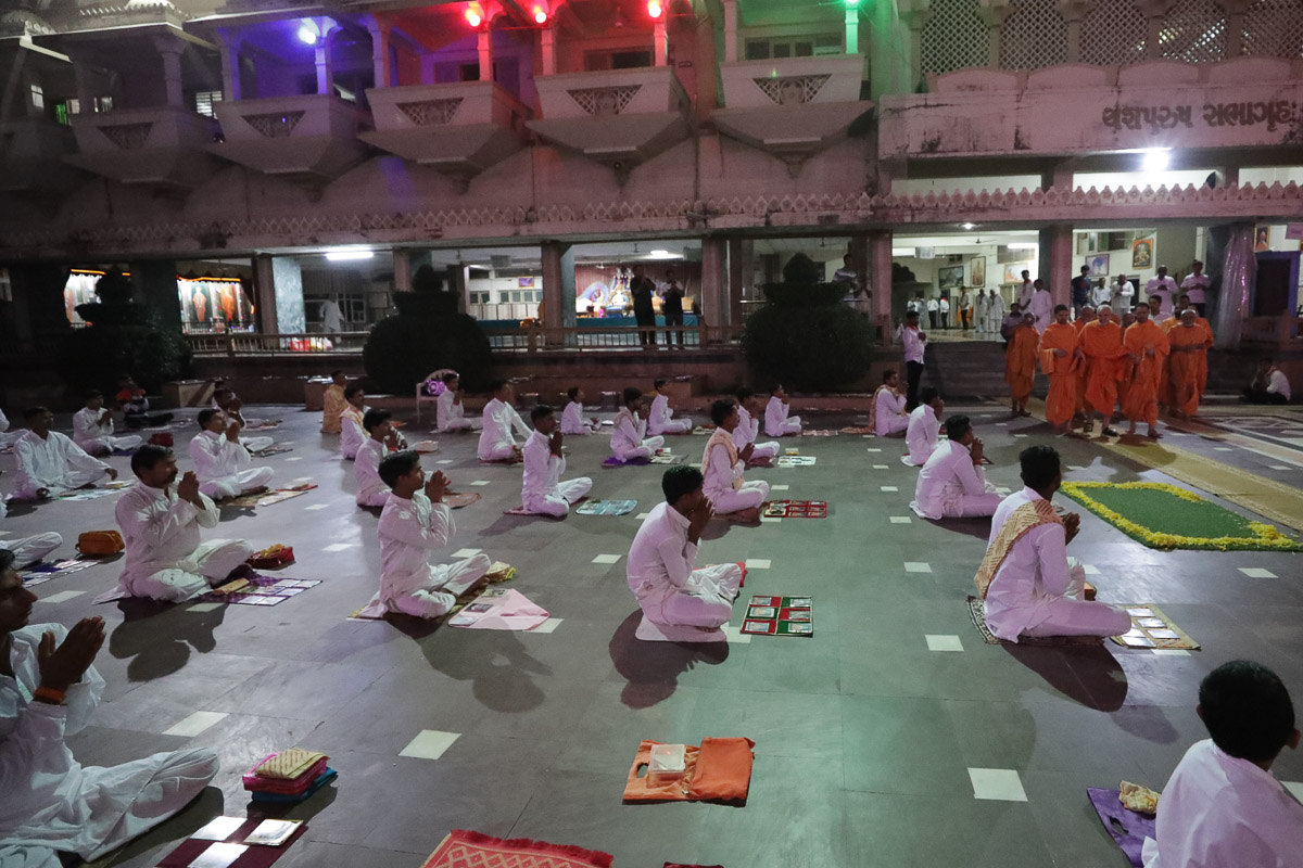 Param Pujya Mahant Swami Maharaj observes youths performing samuh puja in the mandir grounds 