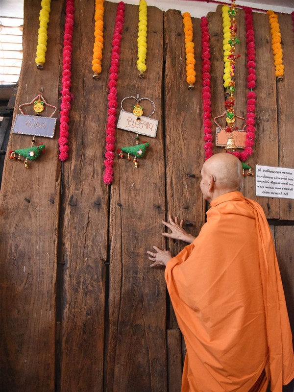 Swamishri reverentially touches the door of Jagrup Barot's house in Sinjiwada (Kutch) sanctified by Bhagwan Swaminarayan