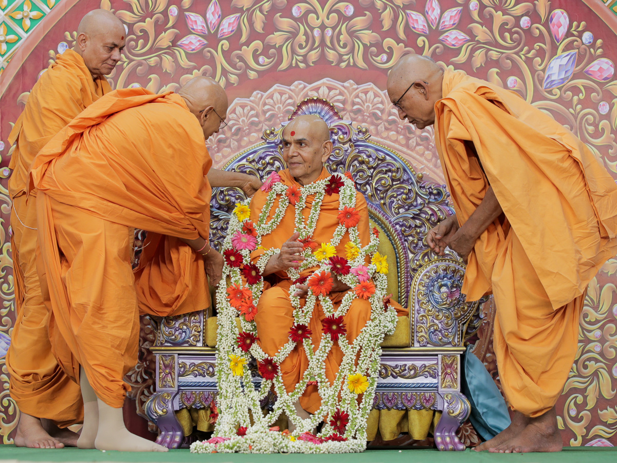 Pujya Bhaktipriya Swami (Pujya Kothari Swami), Pujya Tyagvallabh Swami and Pujya Viveksagar Swami honor Swamishri with a flower shawl