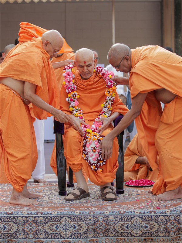 Pujya Tyagvallabh Swami and Vedagna Swami honor Swamishri with a garland