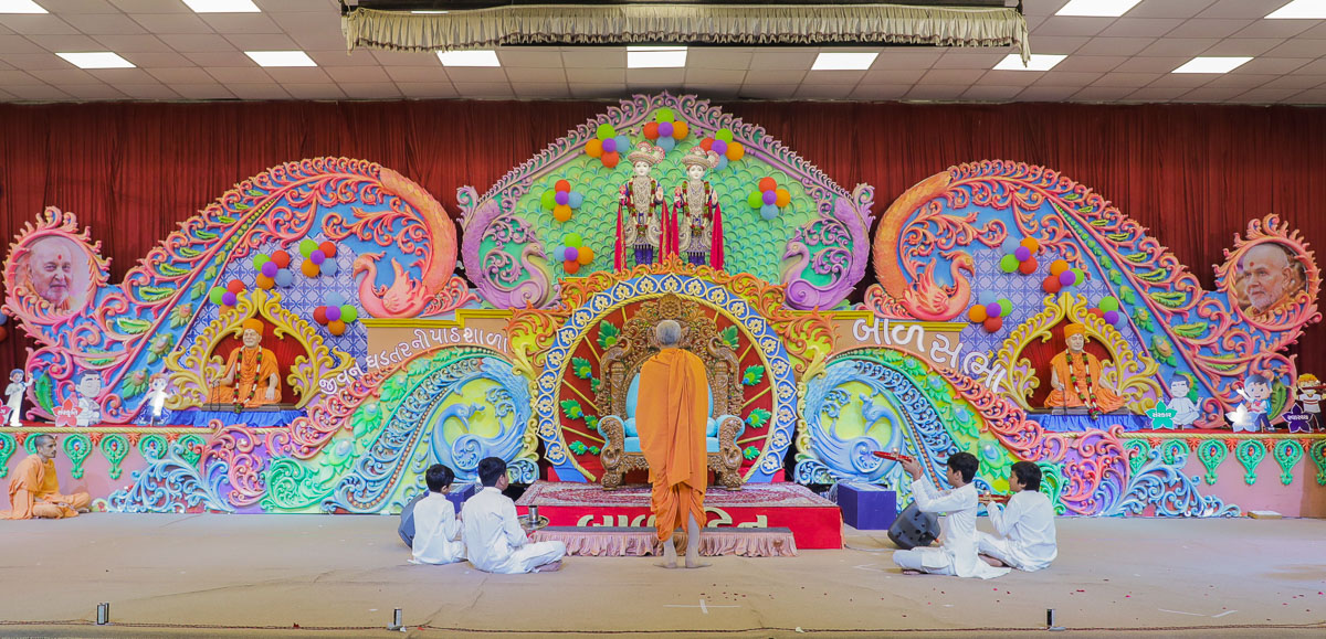 Swamishri and children perform the evening arti