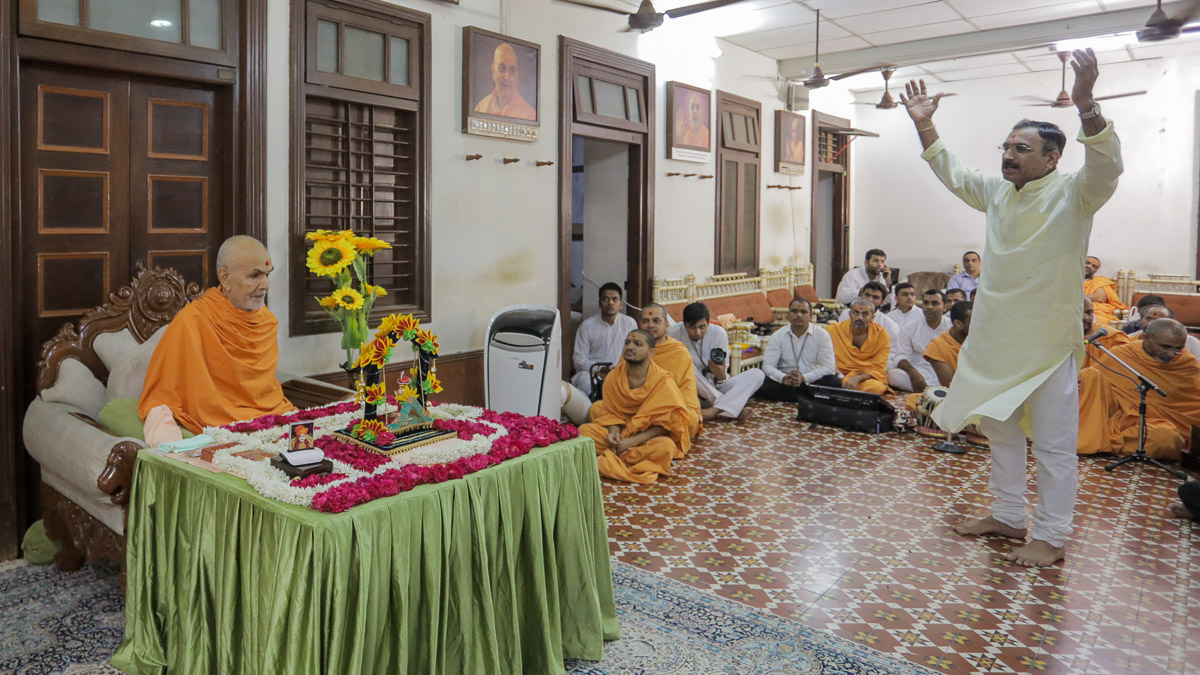 A devotee hails verses singing the glory of Bhagwan Swaminarayan in Swamishri's daily puja