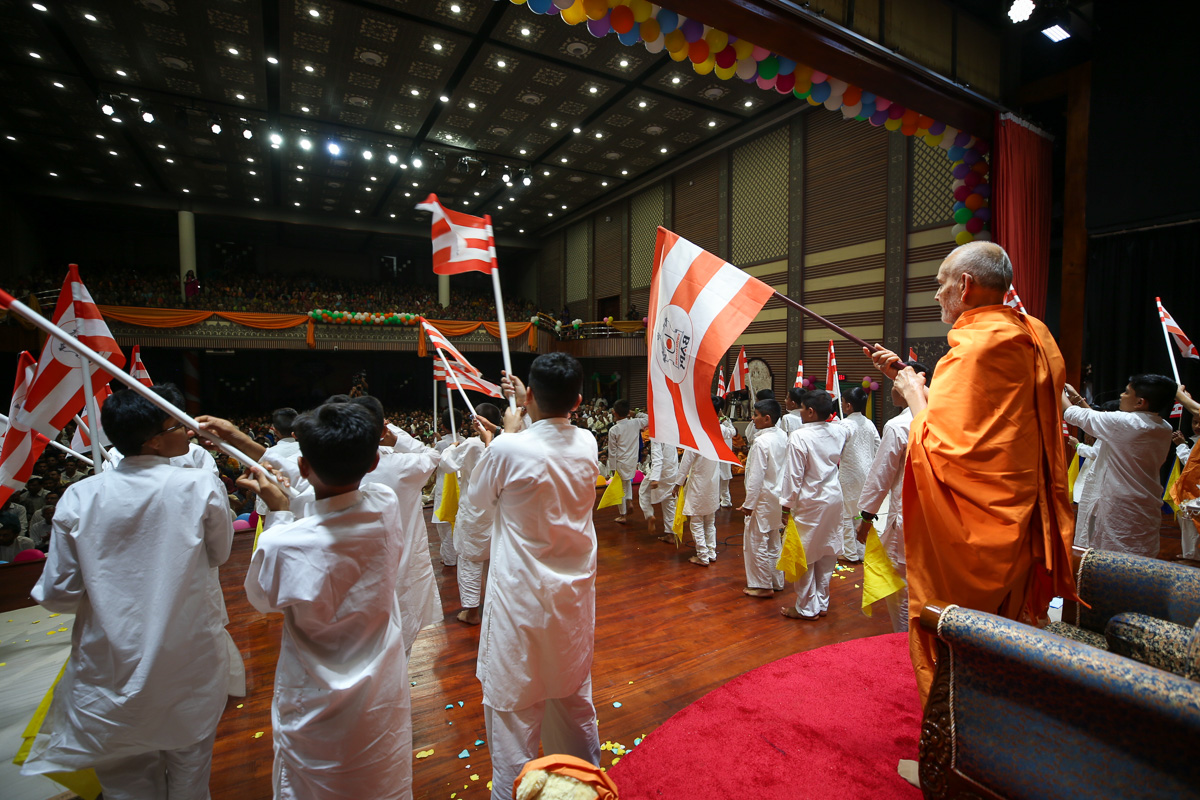 Swamishri and children wave BAPS flags